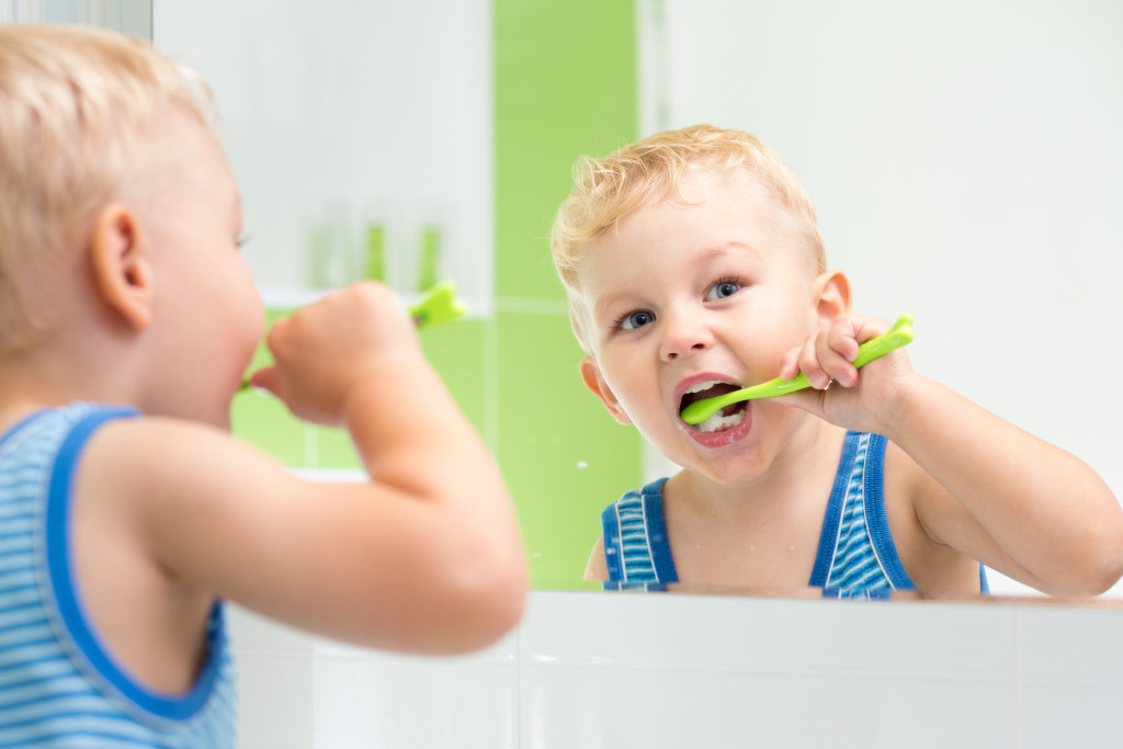 Boy brushing his teeth in the morning with a green tooth brush