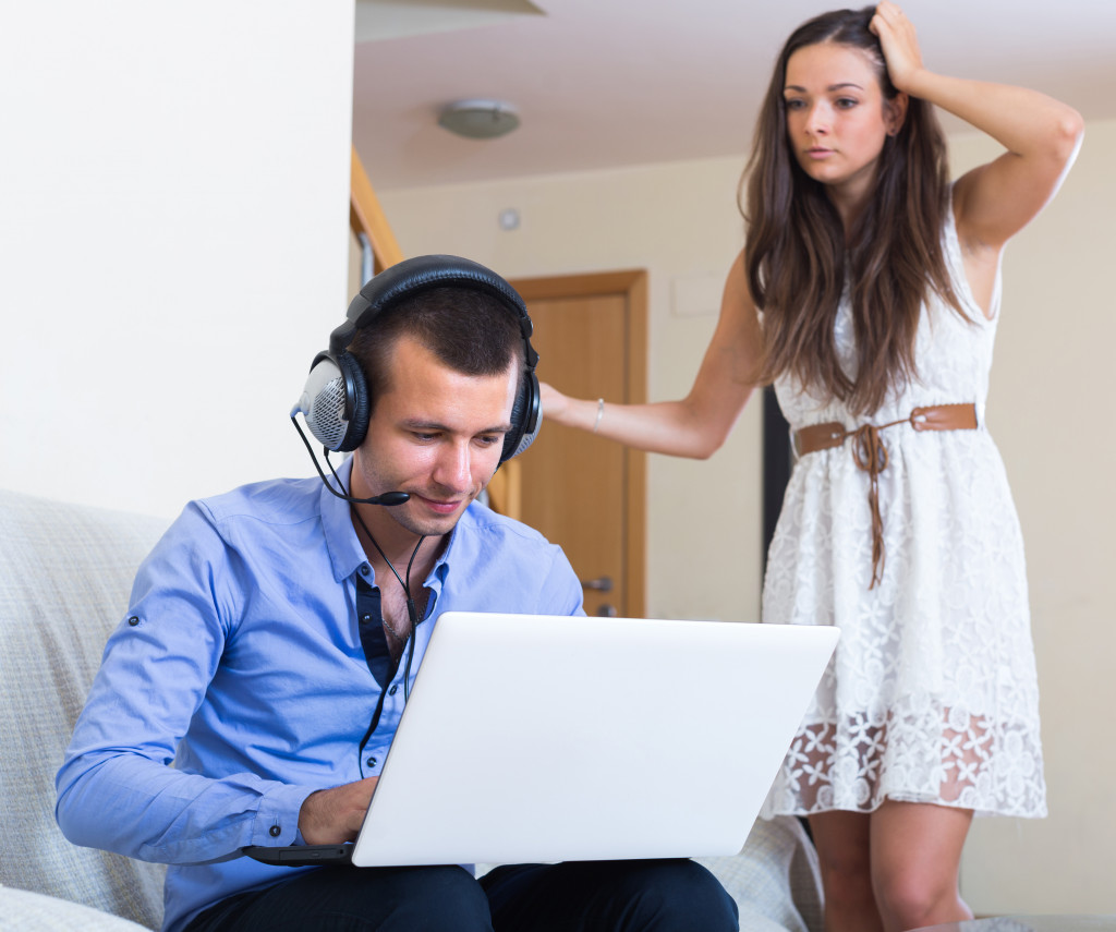 a man using a laptop while wife gets worried