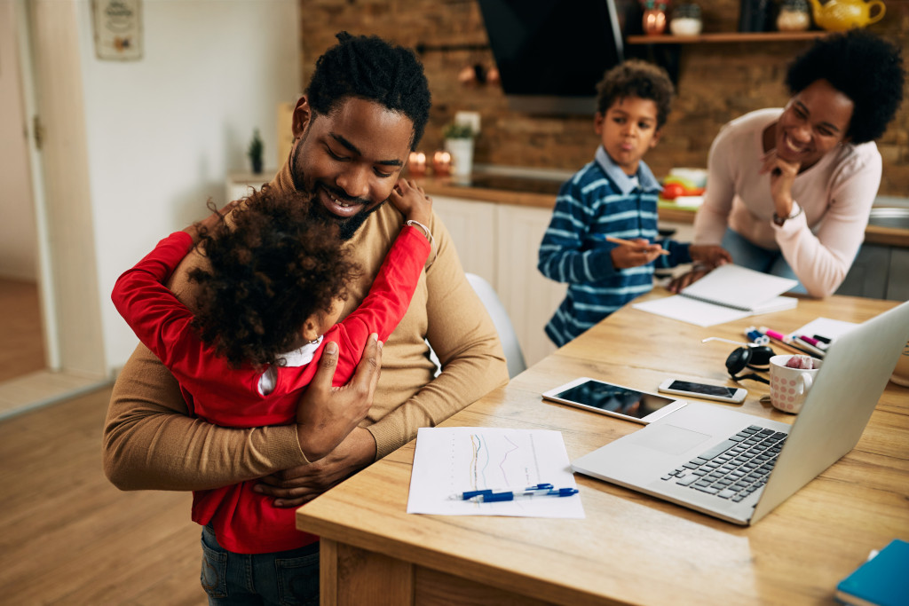 daughter hugging father working in the table with laptop