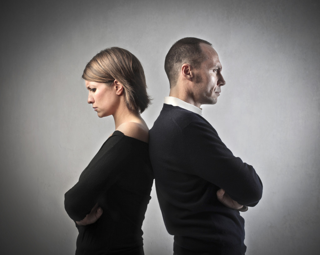 a male and a female standing behind each other, looking away from one another